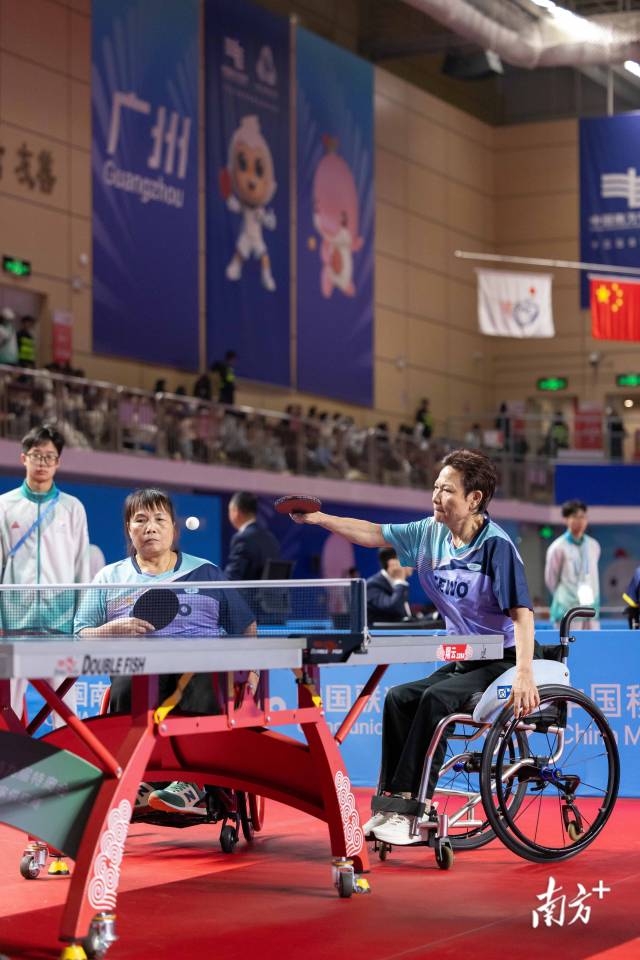 12月8日，在兵乓球TT5女子双打小组赛中，黄丽明（右）撑起身子击球。