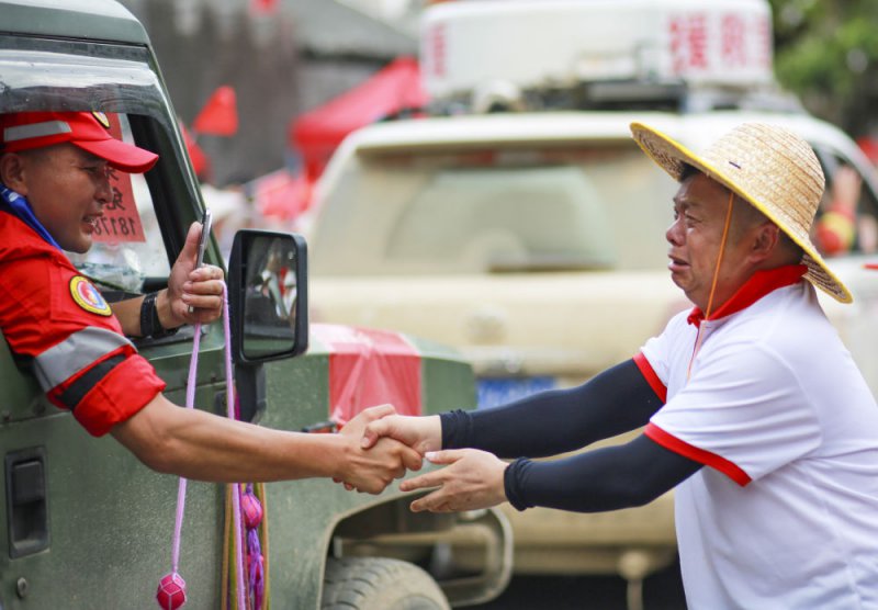 2025年7月3日，在贵州省榕江县，一名救援队员在撤离时与当地居民握手道别。新华社发（龙顺伟摄）