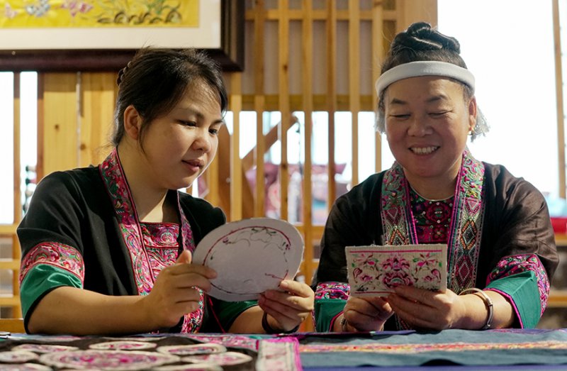 韦清花（右）与女儿覃桂珍交流侗绣制作工艺。杨晓雷摄