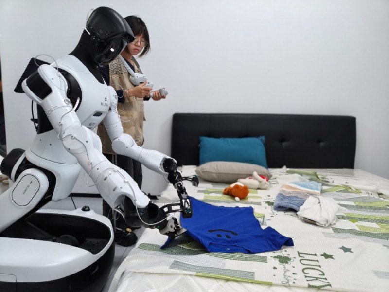 7月30日,浙江清华柔性电子技术研究院具身智能实训场里,00后数据采集员杨慧琴正在训练机器人叠衣服。中青报·中青网记者 宁迪/摄