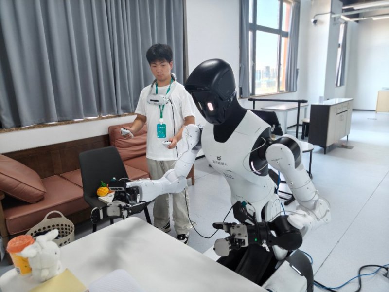 7月30日,浙江清华柔性电子技术研究院具身智能实训场里,来自郑州信息科技职业学院的学生朱思凯作为实习生,正在训练机器人抓取桌上的物件。第一次尝试做数据采集,他觉得很新奇,也希望未来有一天人机协同能有更大的突破。中青报·中青网记者 宁迪/摄